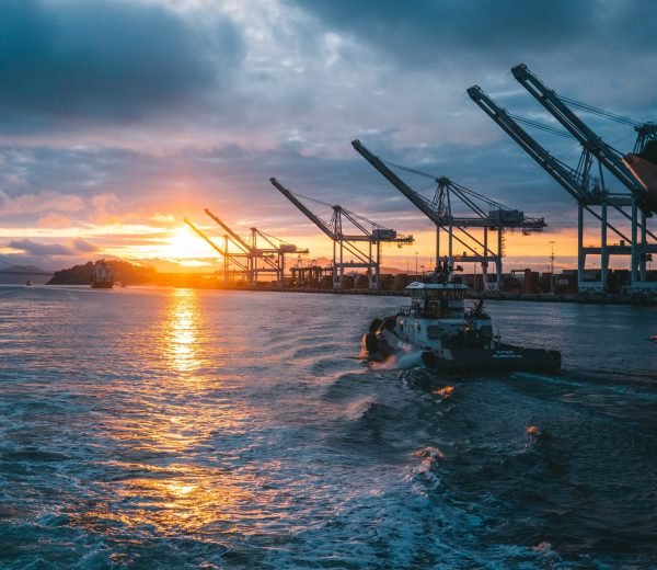 a panoramic shot of oil rigs at sea with a beautiful sunset in the background, under cloudy sky